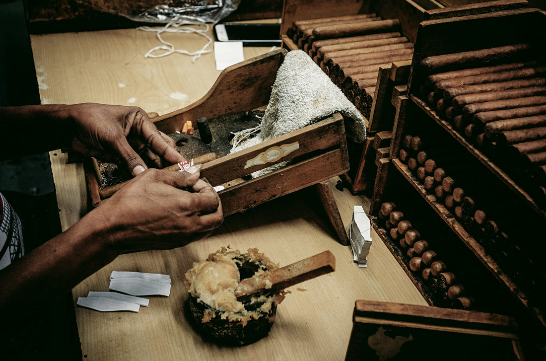 Hands rolling cigars in a workshop with wooden molds